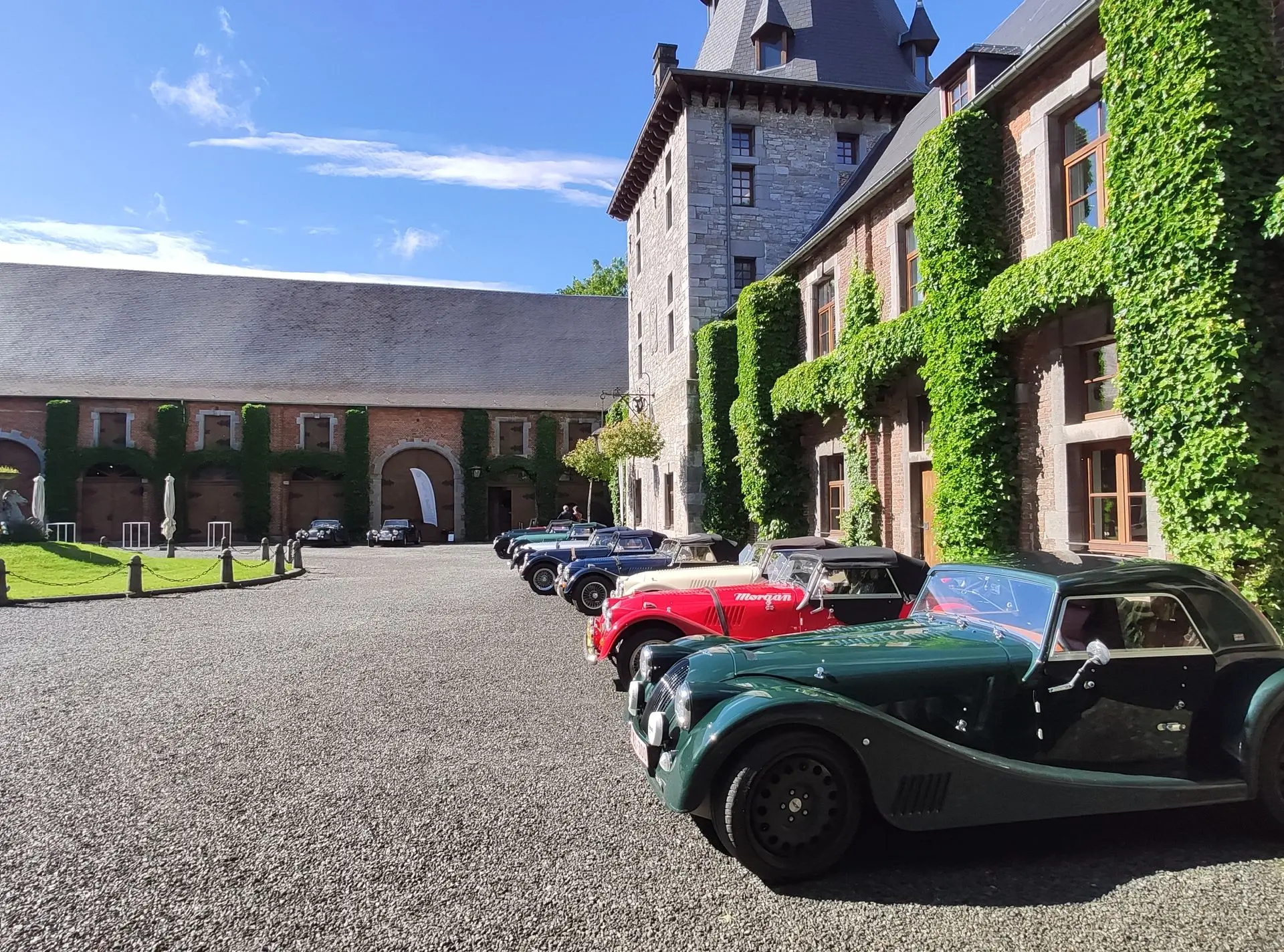 Classic cars lined up in the cobbled courtyard of a château