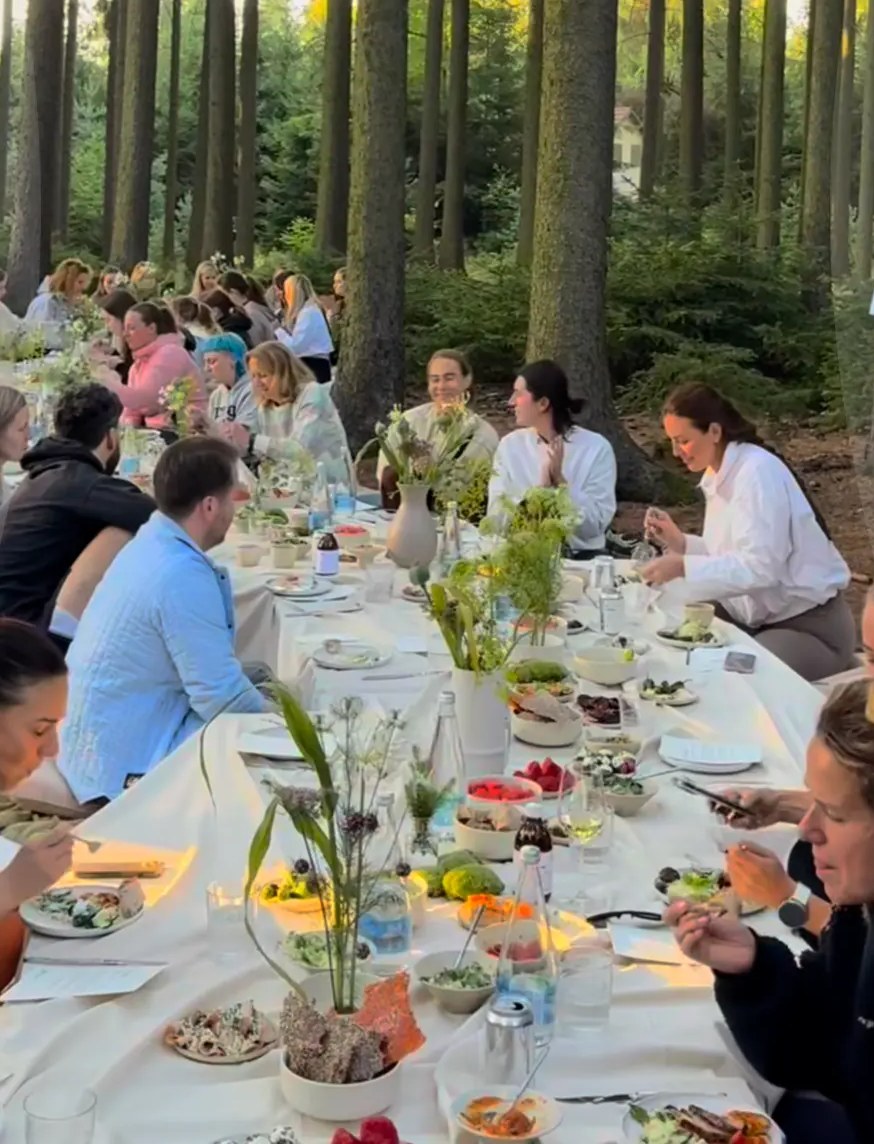 Des collaborateurs réunis autour d’une longue table pour une fête du personnel en forêt.
