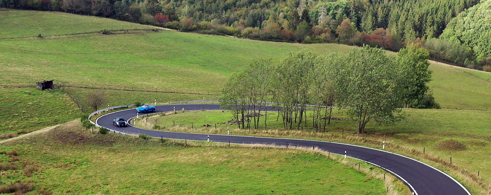 Voitures de collection parcourant une route sinueuse à travers la campagne