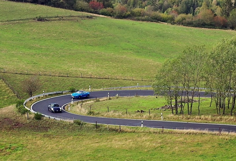 Classic cars on a winding road through the hills